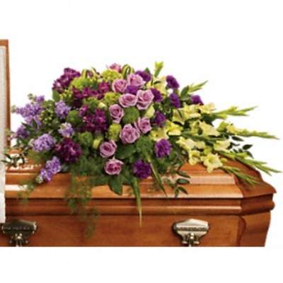 Purple and lavender floral spray on a wooden casket