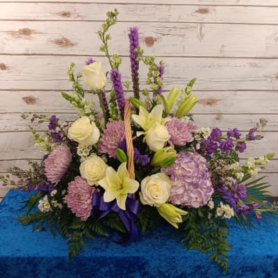 Lavender and cream floral arrangement with roses, lilies, and hydrangea in a basket