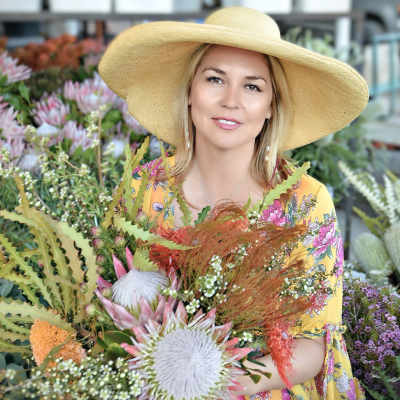 Woman in a wide-brim hat holding a colorful bouquet in a flower shop