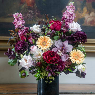 Mixed bouquet in a black vase with roses, orchids, and gerbera daisies