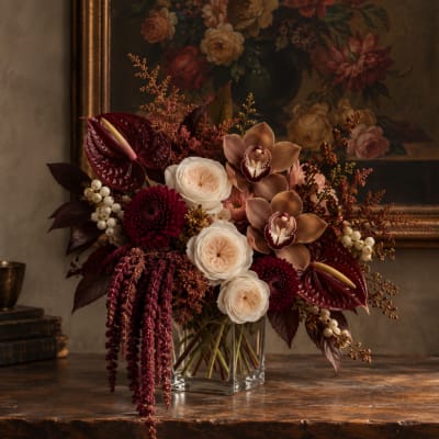 Dark burgundy and cream floral arrangement in a clear glass vase