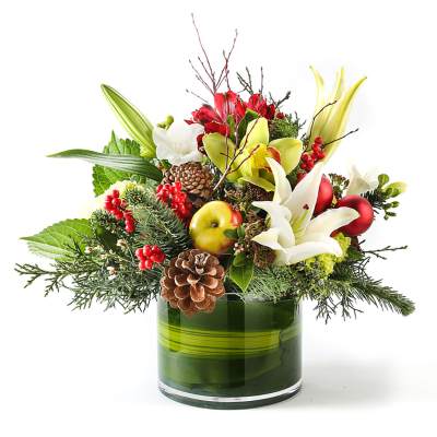 Holiday bouquet with lilies, apples, berries, and pinecones in a green glass vase