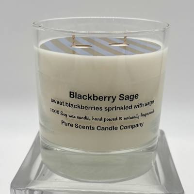 White Blackberry Sage scented candle in a clear glass jar on a glass stand