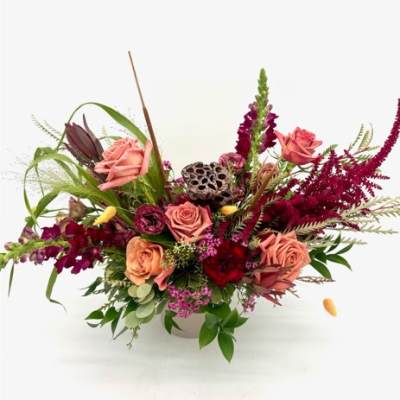 Pink roses and burgundy flowers arranged in a white vase