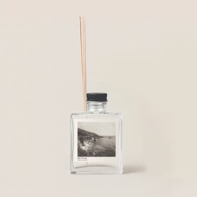 Clear reed diffuser bottle with black cap and wooden reeds