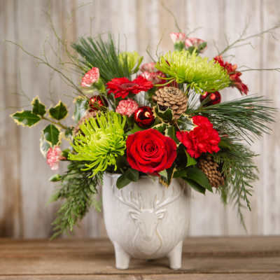 Holiday bouquet with red roses and green chrysanthemums in a white deer vase