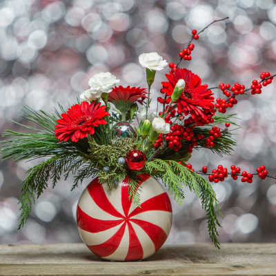 Red and white floral arrangement in a peppermint-striped vase