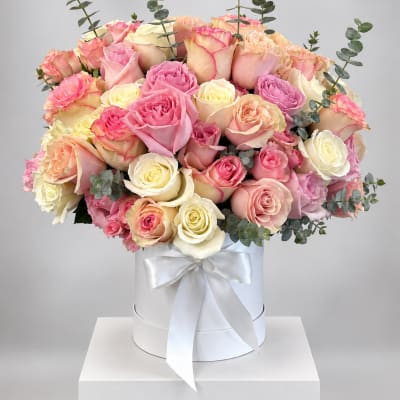 Bouquet of pink, peach, and cream roses in a white hat box with ribbon
