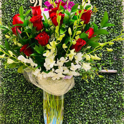 Tall bouquet of red roses and white orchids in a clear glass vase