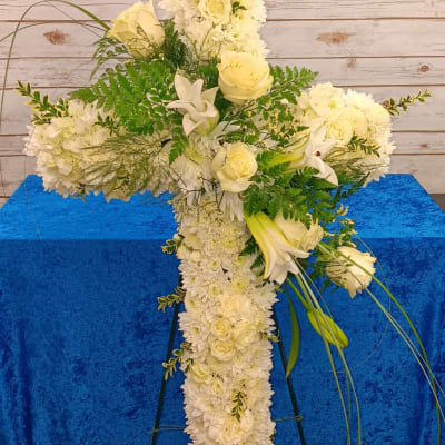 White floral cross arrangement with roses, lilies, and chrysanthemums