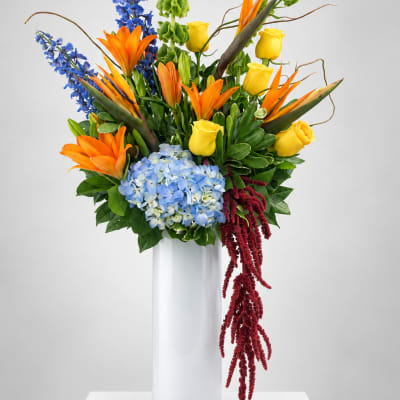 Colorful tropical bouquet in a tall white vase