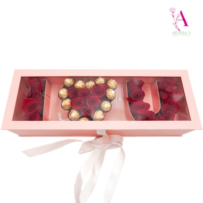 Pink gift box with red roses and gold chocolates arranged inside
