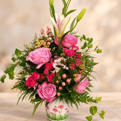 Pink roses and lilies arranged in a decorated white pot