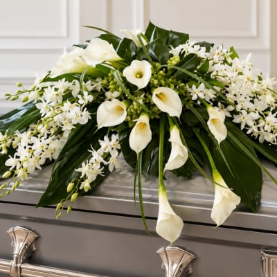 White calla lilies and small white orchids arranged on a casket