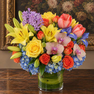 Colorful bouquet of lilies, roses, orchids, and hyacinths in a glass vase