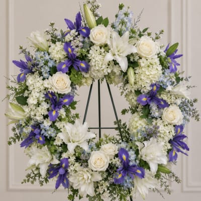 White and purple floral wreath with roses, lilies, and irises on a stand