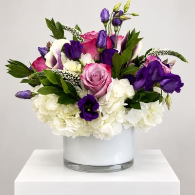 Pink and purple mixed flowers arranged in a clear glass vase
