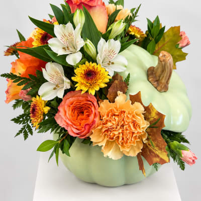 Pumpkin-shaped floral arrangement with orange, white, and yellow blooms