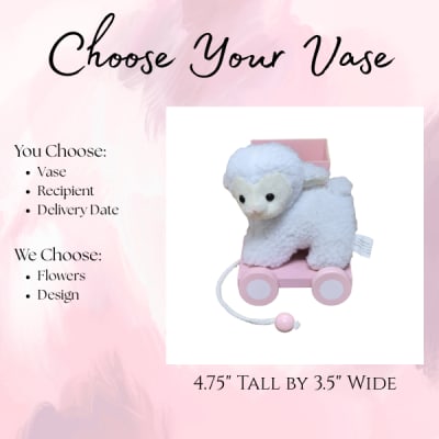 Plush lamb on a pink wheeled cart with a small box behind it
