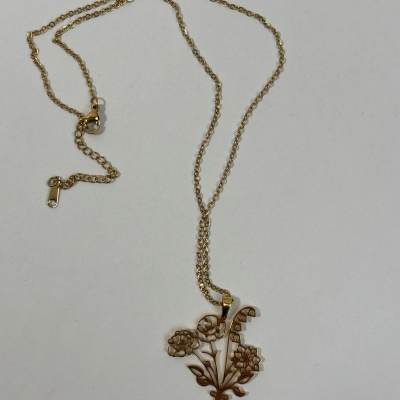 Gold-tone necklace with a floral pendant on a plain background