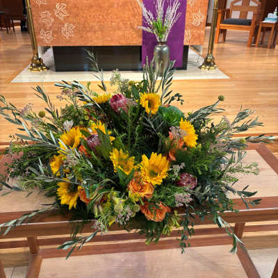 Large floral arrangement with sunflowers and orange blooms on a church altar