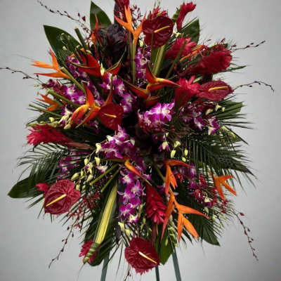Large tropical standing arrangement with red anthuriums, orchids, and orange bird-of-paradise