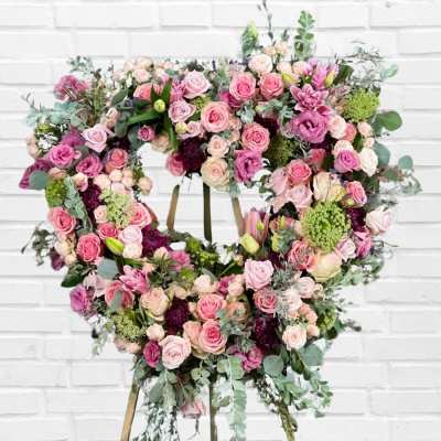 Heart-shaped floral wreath with pink roses and mixed blooms