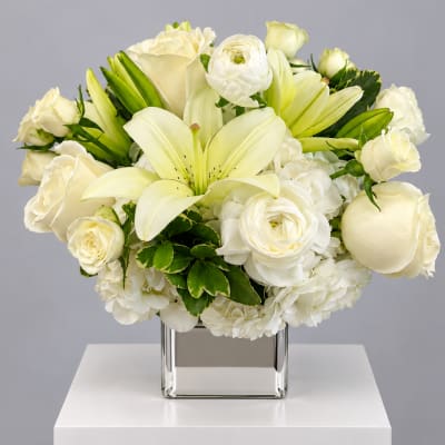 White roses and lilies arranged in a square glass vase