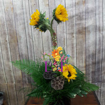 Sunflower arrangement in a black vase with decorative accents