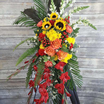 Standing floral spray with sunflowers, roses, and red gladiolus