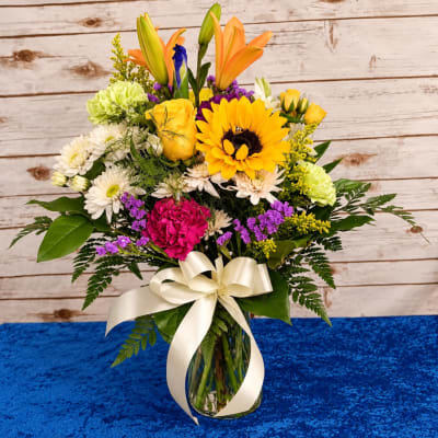 Mixed bouquet in a glass vase with a cream ribbon
