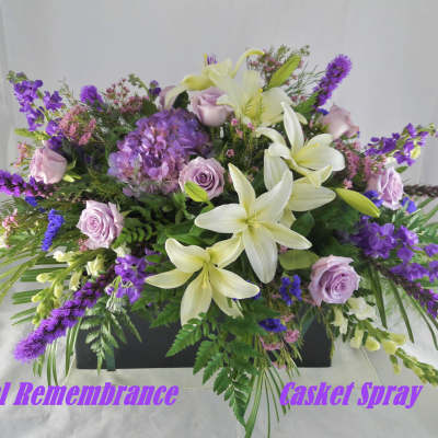 Purple and white casket spray with lilies, roses, and hydrangea