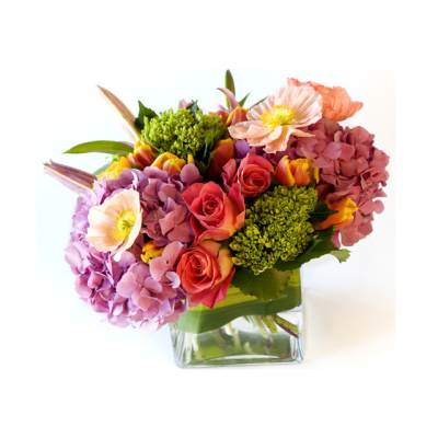 Mixed bouquet of pink and coral flowers in a clear glass vase