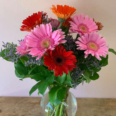 Bouquet of pink, red, and orange gerbera daisies in a glass vase