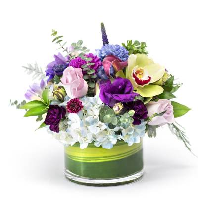 Mixed bouquet of purple, pink, white, and blue flowers in a glass vase