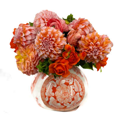 Round arrangement of orange and pink dahlias and roses in a patterned ceramic vase