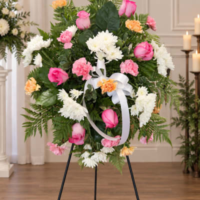 Standing floral wreath with pink and white flowers on an easel