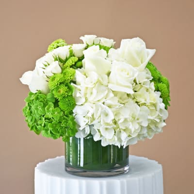 White roses and hydrangeas with green mums in a glass vase