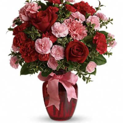 Red roses and pink carnations in a red vase with a pink ribbon