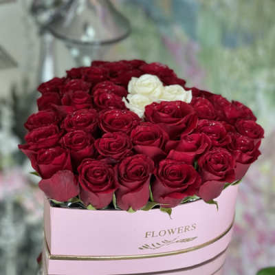 Red and white roses arranged in a pink hat box