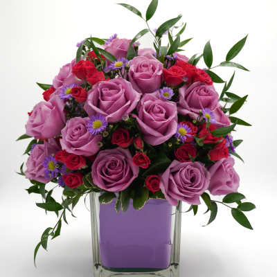 Lavender and red rose bouquet in a clear square vase