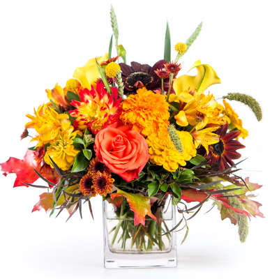 Autumn bouquet of orange and yellow flowers in a clear glass vase