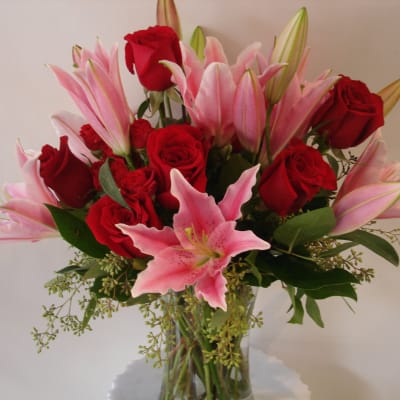 Bouquet of red roses and pink lilies in a clear glass vase