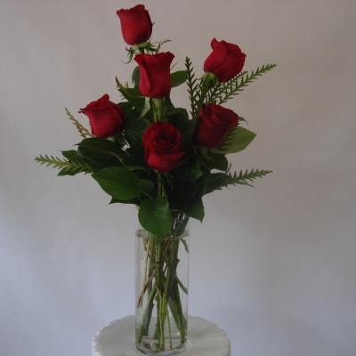 Six red roses in a clear glass vase