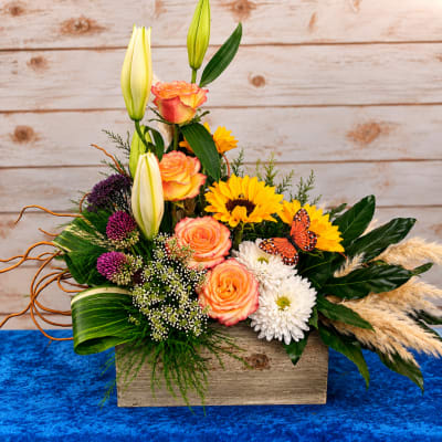 Mixed bouquet in a wooden box with roses, lilies, and sunflowers