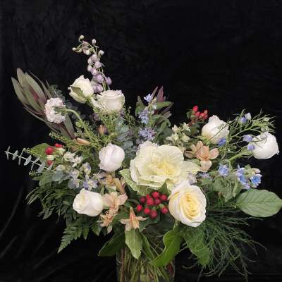 Mixed bouquet of white roses and pastel flowers in a glass vase