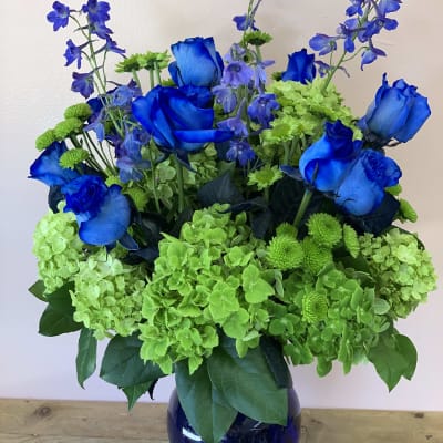 Blue roses and green hydrangeas in a dark glass vase