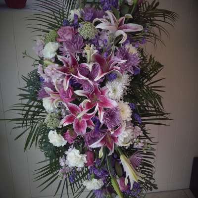 Standing spray of pink lilies, purple flowers, and white blooms