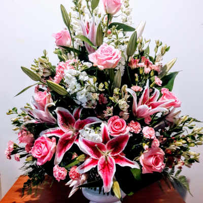 Pink roses and lilies arranged in a white vase