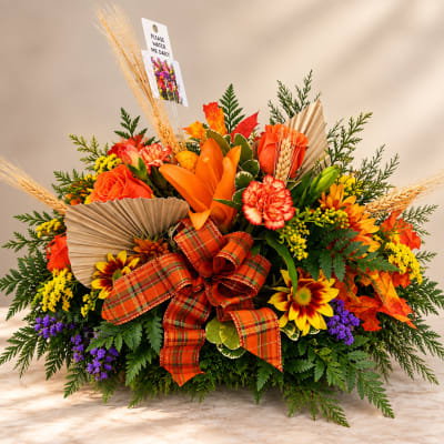 Autumn floral arrangement with orange and yellow blooms and a plaid ribbon